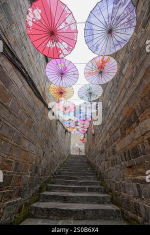 QIANDONGNAN, CINA - 26 DICEMBRE 2024 - ombrelli di carta ad olio sospesi sopra Fuxing Lane si trova su Fuxing Lane nell'antica città di Zhenyuan, Qiandongnan mi Foto Stock