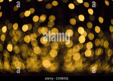 molti bokeh provenienti dai tubi delle lampadine di una strada di notte sembrano luci dorate di lusso su uno sfondo scuro Foto Stock