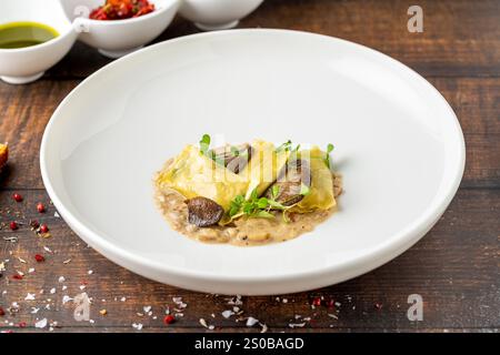 Ravioli di funghi in porcellana bianca su tavola di legno Foto Stock