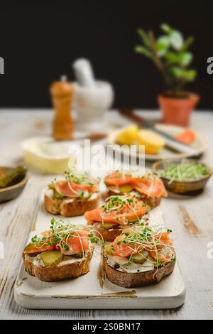 Panini a vista preparati al momento con salmone affumicato, sottaceti e germogli di crescione su pane croccante Foto Stock