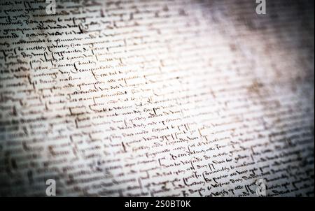 Una vista ravvicinata di un antico manoscritto con intricato testo scritto a mano e inchiostro sbiadito, che mostra scritti storici su carta invecchiata. Foto Stock