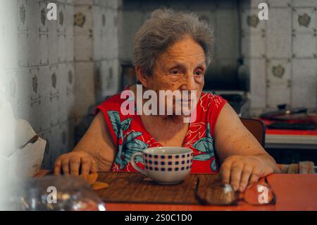 La solitudine degli anziani. Una donna anziana fa colazione da sola in cucina Foto Stock