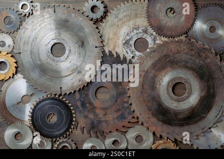Vecchie lame per sega circolare e ruote smeriglio su un tavolo in legno, primo piano, vista dall'alto. Utensili per carpenteria, attrezzature per segare e rettificare Foto Stock