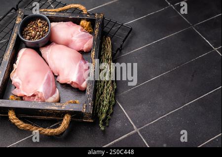 Filetti di cosce di pollo crude in un vassoio di legno fondo nero. vista dall'alto. Foto Stock