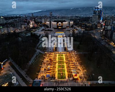 Vista aerea notturna del Palazzo Nazionale della Cultura (NDK) di Sofia, Bulgaria, con bancarelle illuminate per il mercato di Natale, vivaci luci della città, e. Foto Stock
