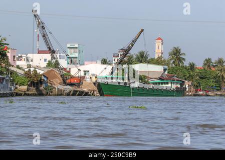 Mekong Delta, Vietnam. 27 dicembre 2024: Una nave da carico/chiatta carica o scarica sabbia. L'estrazione di sabbia e ghiaia (miniere o draghe) utilizzata per l'industria edile solleva avvertimenti circa l'impatto ambientale dell'eccessivo sfruttamento dei sedimenti dei fiumi (biodiversità e ecosistema), ma anche sulla vita delle persone che vivono sulle rive del fiume. Lo sfruttamento legale o illegale della sabbia provoca una massiccia erosione delle banche, con conseguente perdita di terreni agricoli, crolli di edifici o case e delocalizzazioni della popolazione. Crediti: KEVIN IZORCE/Alamy Live News Foto Stock