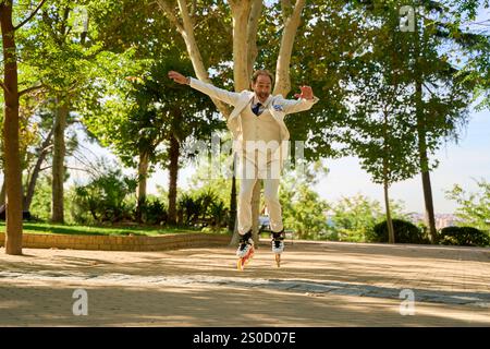 Uomo che fa un salto sui pattini a rotelle in un parco soleggiato Foto Stock