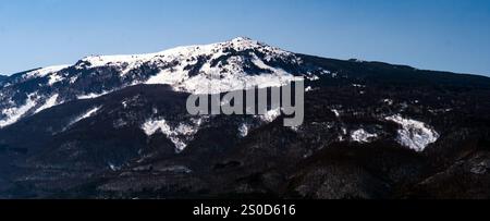 La catena montuosa innevata di Vitosha sotto un cielo azzurro e limpido, con macchie di foresta visibili sulle pendici. Foto Stock