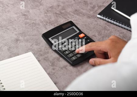 Primo piano delle mani di un uomo d'affari usando una calcolatrice in ufficio Foto Stock