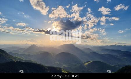 Una vista mozzafiato del tramonto su un tranquillo paesaggio di dolci colline e lontane catene montuose. Foto Stock