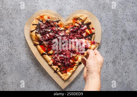 Cibo per San Valentino. Pizza dolce a forma di cuore con ananas su sfondo grigio. Vista dall'alto. Cena romantica. Foto Stock