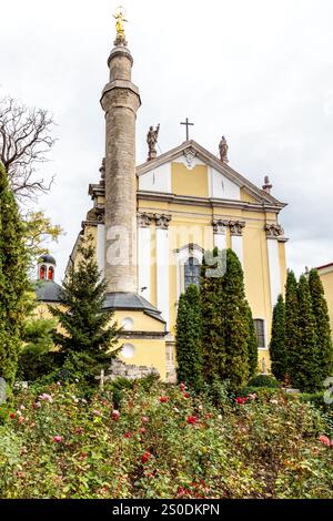 Un alto edificio con una croce sulla sommità e una grande colonna. L'edificio e' circondato da alberi e presenta un giardino davanti ad esso Foto Stock