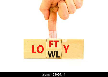 Simbolo alto o basso. Parole concettuali Lofty lowly su blocco di legno. Bellissimo sfondo bianco del tavolo. Mano d'affari. Business lofty o lowly co Foto Stock