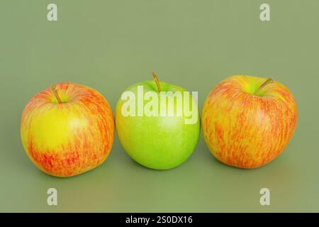 Due mele rosse e gialle e una mela verde. Frutta, mele su sfondo verde Foto Stock