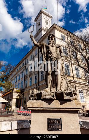 Una statua di un uomo che regge una lancia e una statua di una donna che tiene un pesce. La statua si trova di fronte a un edificio con un orologio sopra Foto Stock