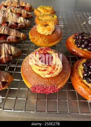 Ciambella Berliner con panna montata e ciliegia su una griglia in filo metallico in vendita Foto Stock