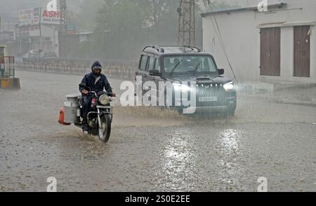 Beawar, Rajasthan, India, 27 dicembre 2024: I veicoli attraversano strade bagnate in mezzo alla pioggia la mattina d'inverno a Beawar. La vita quotidiana nel Rajasthan è stata gravemente colpita dalla pioggia e dalla nebbia che hanno colpito lo stato, portando a un brusco calo delle temperature e a una ridotta visibilità in diverse aree. Il tempo inclemente ha intensificato il freddo, con una fitta nebbia che ricopre molte regioni. L'India Meteorological Department (IMD) ha emesso un allarme arancione per 15 distretti e un allarme giallo per sei distretti nello stato, avvertendo della persistente nebbia densa nei prossimi tre giorni. Crediti: Sumit Saraswat / Alam Foto Stock