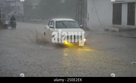 Beawar, Rajasthan, India, 27 dicembre 2024: I veicoli attraversano strade bagnate in mezzo alla pioggia la mattina d'inverno a Beawar. La vita quotidiana nel Rajasthan è stata gravemente colpita dalla pioggia e dalla nebbia che hanno colpito lo stato, portando a un brusco calo delle temperature e a una ridotta visibilità in diverse aree. Il tempo inclemente ha intensificato il freddo, con una fitta nebbia che ricopre molte regioni. L'India Meteorological Department (IMD) ha emesso un allarme arancione per 15 distretti e un allarme giallo per sei distretti nello stato, avvertendo della persistente nebbia densa nei prossimi tre giorni. Crediti: Sumit Saraswat / Alam Foto Stock