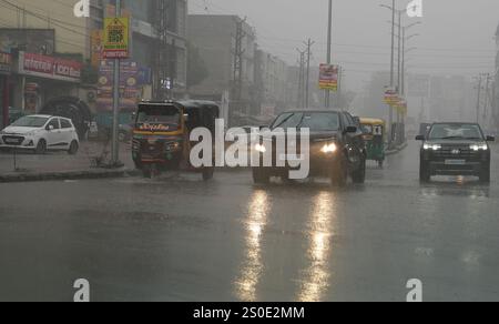 Beawar, Rajasthan, India, 27 dicembre 2024: Pendolari in una strada in mezzo alla pioggia la mattina d'inverno a Beawar. La vita quotidiana nel Rajasthan è stata gravemente colpita dalla pioggia e dalla nebbia che hanno colpito lo stato, portando a un brusco calo delle temperature e a una ridotta visibilità in diverse aree. Il tempo inclemente ha intensificato il freddo, con una fitta nebbia che ricopre molte regioni. L'India Meteorological Department (IMD) ha emesso un allarme arancione per 15 distretti e un allarme giallo per sei distretti nello stato, avvertendo della persistente nebbia densa nei prossimi tre giorni. Crediti: Sumit Saraswat / Alamy Live ne Foto Stock