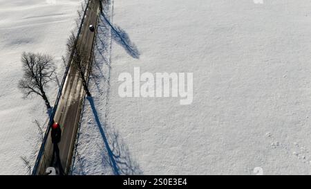 Ripresa aerea ad alto angolo di una strada rurale che attraversa un vasto paesaggio innevato. Foto Stock