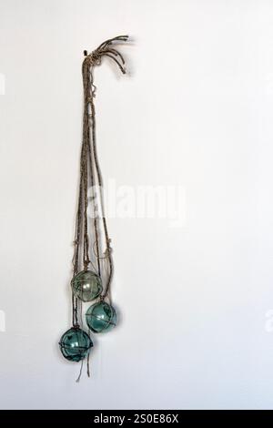 I galleggianti decorativi della rete in vetro sono appesi su una parete interna Foto Stock