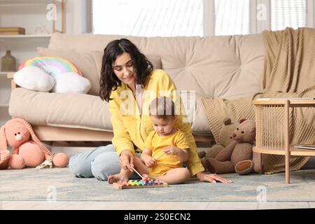 Bella, giovane, felice madre e piccolo bambino che gioca con lo xilofono a casa Foto Stock