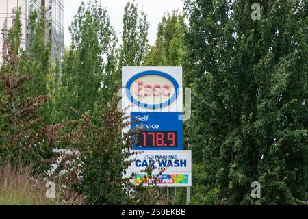 Burnaby, CANADA - JUL 17 2024 : cartello del prezzo del carburante presso una stazione di servizio esso che mostra le tariffe del carburante self-service, circondato da alberi verdi e vegetazione urbana. Foto Stock