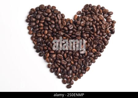 Chicchi di caffè tostati disposti a forma di cuore isolati su sfondo bianco. Foto Stock