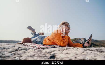 Donna rilassante in cima a una montagna con uno smartphone Foto Stock