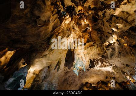 una grotta con stalagmiti e stalattiti. La grotta è grande e scura e le pareti sono coperte da una varietà di formazioni rocciose diverse. Lo stalagmi Foto Stock