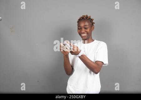 Bella signora nigeriana che conta i soldi con un sorriso sul viso Foto Stock