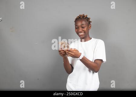 Bella signora nigeriana che conta i soldi con un sorriso sul viso Foto Stock