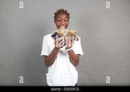 Bella signora nigeriana che conta i soldi con un sorriso sul viso Foto Stock