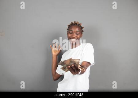 Bella signora nigeriana che conta i soldi con un sorriso sul viso Foto Stock