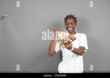 Bella signora nigeriana che conta i soldi con un sorriso sul viso Foto Stock