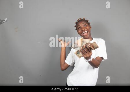 Bella signora nigeriana che conta i soldi con un sorriso sul viso Foto Stock