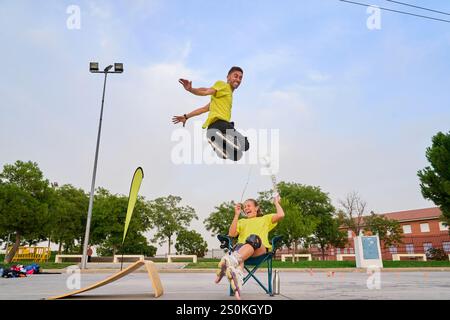 Rollerblader che fa un salto in alto su una donna che ride in un parco all'aperto Foto Stock