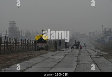 PRAYAGRAJ, INDIA - DICEMBRE 28: Lavoratori che posano lastre a scacchi a Mahakumbh Nagar il 28 dicembre 2024 a Prayagraj, India. Il prossimo Maha Kumbh Mela si svolgerà a Prayagraj dal 13 gennaio al 26 febbraio 2025. Si prevede che il festival attirerà oltre 400 milioni di pellegrini. Crediti: SIPA USA/Alamy Live News Foto Stock