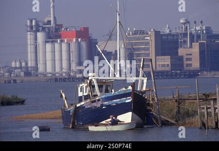 Off grid Living, Broadness Creek, Swanscombe Peninsula, vecchie barche a vela ancora in vita, uomo in barca a remi. Fabbriche sul lato nord dell'estuario del Tamigi nell'Essex. North Kent, Borough of Dartford Inghilterra 1991 1990s UK HOMER SYKES. Foto Stock