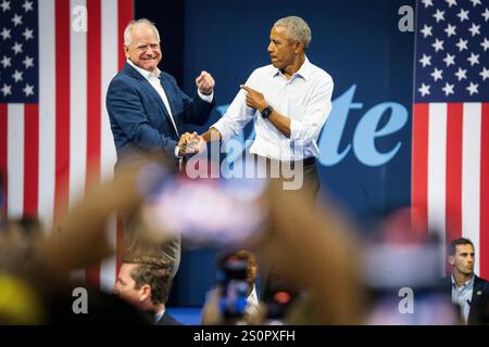 L'ex presidente Barack Obama stringe la mano a Tim Walz, candidato al vp, sul palco di una manifestazione durante la campagna presidenziale del 2024. Foto Stock