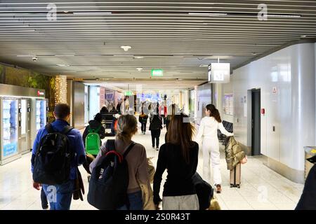 Francoforte sul meno, Assia, Germania - 28 dicembre 2024: I passeggeri si spostano attraverso un ampio corridoio dell'aeroporto, dotato di segnaletica e illuminazione moderna. Quest'area funge da collegamento tra i terminal e i cancelli, ma non è una passerella, ma un corridoio aeroportuale interno. *** Passagiere bewegen sich durch einen breiten Gang im Flughafen, der mit Hinweisschildern und moderner Beleuchtung ausgestattet ist. Dieser Bereich Dient als Verbindung zwischen Terminals und Gates, jedoch handelt es sich nicht um eine Gangway, sondern um einen internen Flughafenkorridor. Foto Stock