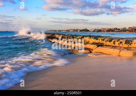 L'oceano si sta schiantando contro una costa rocciosa. Le onde sono bianche e schiumose, e l'acqua è di colore blu intenso. La scena è tranquilla e serena, Foto Stock