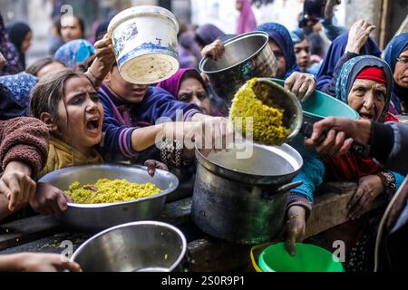 Pechino, Cina. 27 dicembre 2024. I palestinesi ricevono cibo gratuito da un centro di distribuzione di cibo a Gaza City, il 27 dicembre 2024. Crediti: Mahmoud Zaki/Xinhua/Alamy Live News Foto Stock