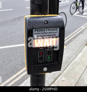 Pulsante di controllo del semaforo pedonale sul passaggio pedonale per un attraversamento sicuro della strada a Londra, indicando il segnale di attesa Foto Stock