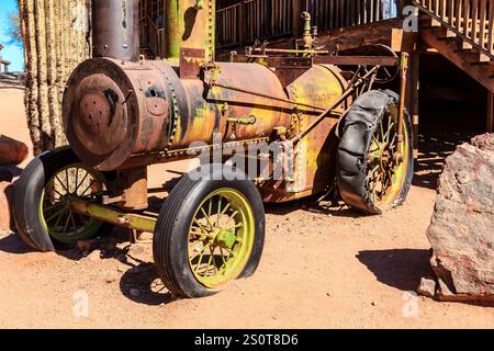 Un vecchio motore a vapore arrugginito si trova nel deserto. Il motore è circondato da rocce ed è abbandonato Foto Stock