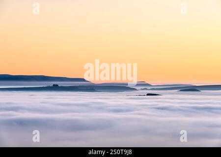 Una vista lontana delle Black Mountains in Galles, Regno Unito, vista sopra un mare di nebbia causata da un'inversione di temperatura e che si estende per 40 km, vista da Stonewall Hill vicino a Knighton sui confini gallesi. Foto scattata durante il clima nebbioso che seguì il Natale 2024 Foto Stock