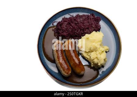 , Deutschland, 29.12.2024, Bratwürste mit dunkler Soße, Rotkohl und cremigem Kartoffelpüree auf einem blauen Teller – ein klassisches deutsches Geric Foto Stock