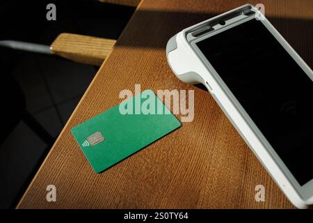 Moderno terminale di pagamento e carte di credito su sfondo in legno, vista dall'alto. Spazio per il testo, Foto Stock