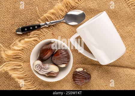 Diverse caramelle di cioccolato con piatti in ceramica su tessuto di iuta, vista dall'alto. Foto Stock