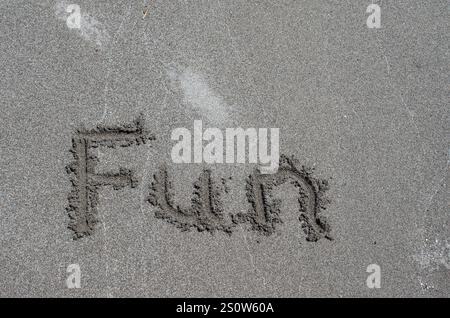 Messaggio di divertimento scritto sulla sabbia della spiaggia. Concetto di gioia, divertimento, felicità e divertimento in spiaggia e nella vita. Foto Stock